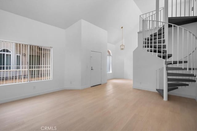 14937 Dickens St Unit 209, Sherman Oaks, CA 91403 - unfurnished living room featuring high vaulted ceiling, wood finished floors, stairs, and baseboards