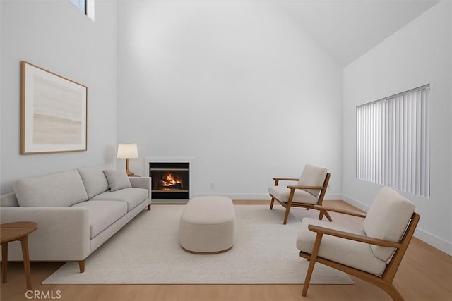 14937 Dickens St Unit 209, Sherman Oaks, CA 91403 - living room featuring high vaulted ceiling, wood finished floors, a warm lit fireplace, and baseboards