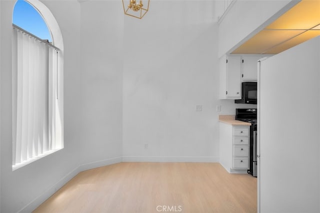 14937 Dickens St Unit 209, Sherman Oaks, CA 91403 - unfurnished dining area with light wood-style floors, a chandelier, and baseboards