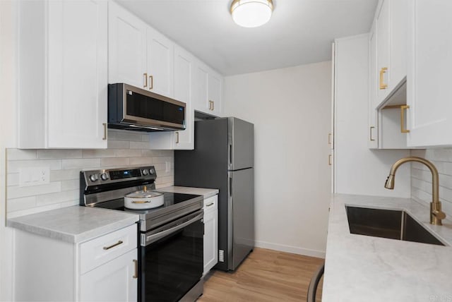 3825 Van Dyke Ave, San Diego, CA 92105 - kitchen with stainless steel appliances, a sink, decorative backsplash, white cabinetry, and baseboards