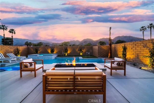 56231 Platinum Way, La Quinta, CA 92253 - view of pool featuring an outdoor living space with a fire pit, a mountain view, a patio area, and a fenced backyard