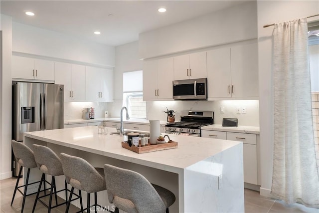 56231 Platinum Way, La Quinta, CA 92253 - kitchen featuring stainless steel appliances, a sink, a breakfast bar, a kitchen island with sink, and light stone countertops