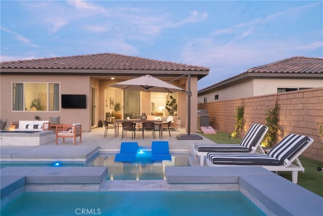 56231 Platinum Way, La Quinta, CA 92253 - rear view of house with an outdoor living space with a fire pit, an in-ground hot tub, fence, a patio area, and a tiled roof