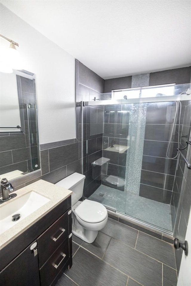 4843 Sumac Pl, Oceanside, CA 92057 - bathroom featuring tile walls, toilet, vanity, a stall shower, and tile patterned floors
