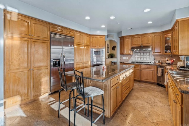28623 Willow Park Rd, Escondido, CA 92026 - kitchen with built in appliances, under cabinet range hood, arched walkways, a center island, and a breakfast bar area