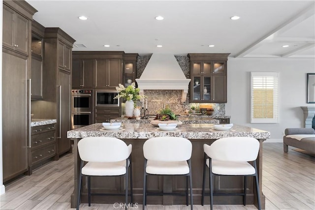 104 Scenic Crst, Irvine, CA 92618 - kitchen featuring custom range hood, double oven, dark brown cabinetry, backsplash, and glass insert cabinets