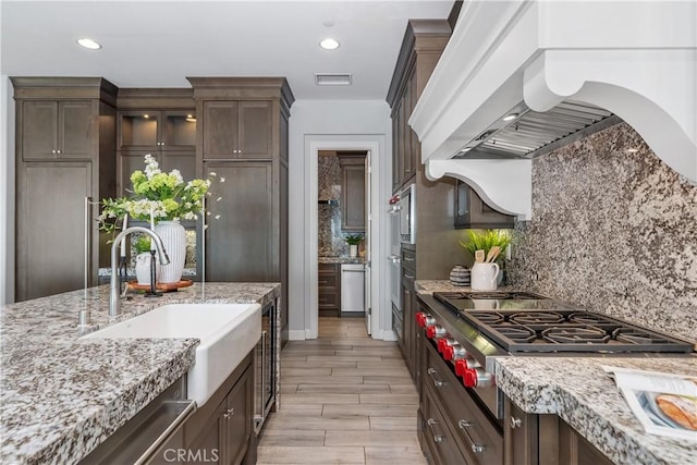 104 Scenic Crst, Irvine, CA 92618 - kitchen featuring a sink, range hood, dark brown cabinets, light stone counters, and stainless steel gas cooktop