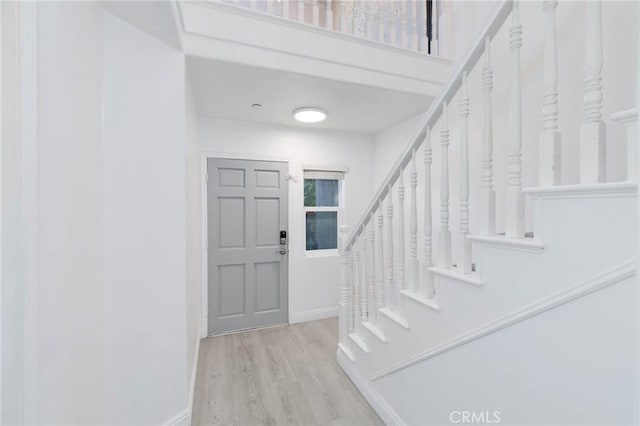 entrance foyer with wood finished floors, baseboards, and stairs