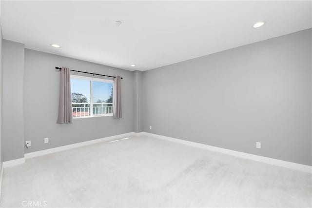 spare room featuring light carpet, recessed lighting, and baseboards