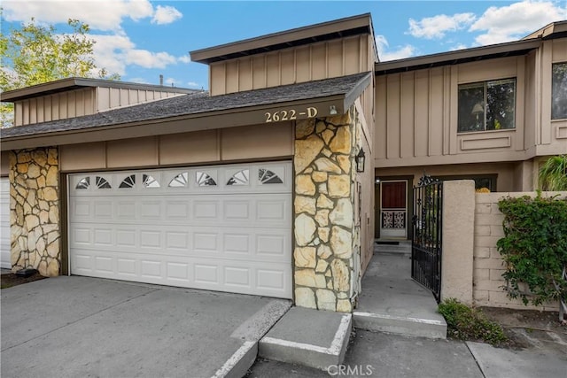 2622 N Tustin Ave Unit 147, Santa Ana, CA 92705 - view of front of house with board and batten siding, stone siding, driveway, an attached garage, and a gate