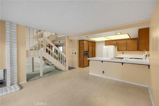 2622 N Tustin Ave Unit 147, Santa Ana, CA 92705 - kitchen featuring brown cabinetry, freestanding refrigerator, a peninsula, baseboards, and a textured ceiling
