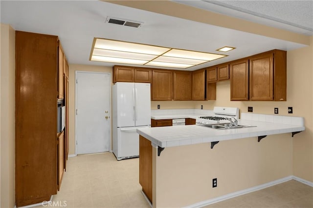 2622 N Tustin Ave Unit 147, Santa Ana, CA 92705 - kitchen with white appliances, a peninsula, brown cabinetry, and tile counters