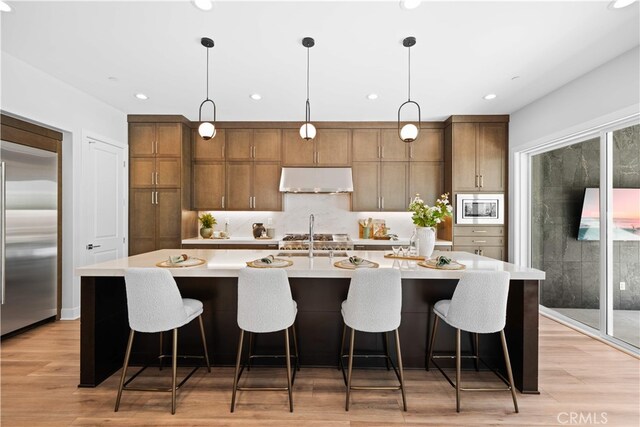 110 Mulberry, Lake Forest, CA 92630 - kitchen with built in appliances, under cabinet range hood, light countertops, a sink, and hanging light fixtures