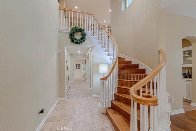 2551 Holly St, Fullerton, CA 92835 - stairway featuring a towering ceiling, arched walkways, tile patterned floors, and baseboards