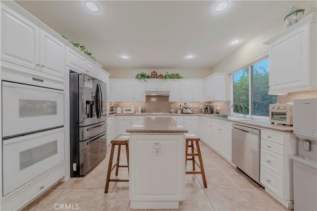 2551 Holly St, Fullerton, CA 92835 - kitchen featuring stainless steel appliances, a breakfast bar area, under cabinet range hood, white cabinets, and recessed lighting