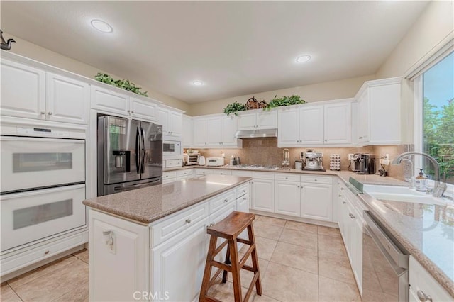 2551 Holly St, Fullerton, CA 92835 - kitchen with stainless steel appliances, under cabinet range hood, a sink, white cabinets, and a center island