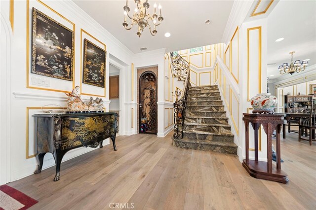 2825 Majestic St, West Covina, CA 91791 - foyer with a chandelier, a decorative wall, stairway, light wood-type flooring, and crown molding