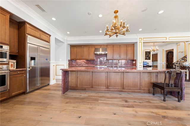 2825 Majestic St, West Covina, CA 91791 - kitchen featuring built in fridge, a chandelier, under cabinet range hood, ornamental molding, and recessed lighting