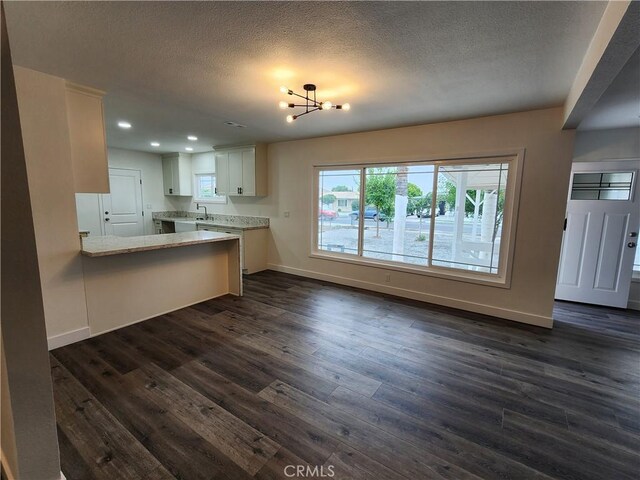 880 S State St, Hemet, CA 92543 - kitchen featuring dark wood finished floors, white cabinets, a textured ceiling, a chandelier, and a peninsula