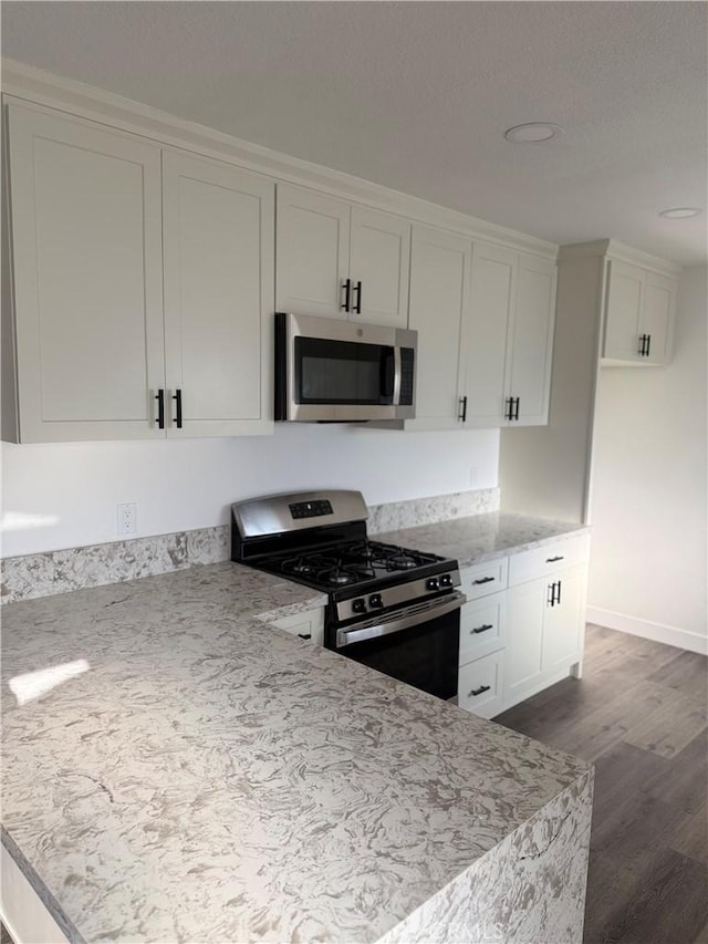 880 S State St, Hemet, CA 92543 - kitchen with appliances with stainless steel finishes, dark wood finished floors, white cabinetry, light stone countertops, and recessed lighting