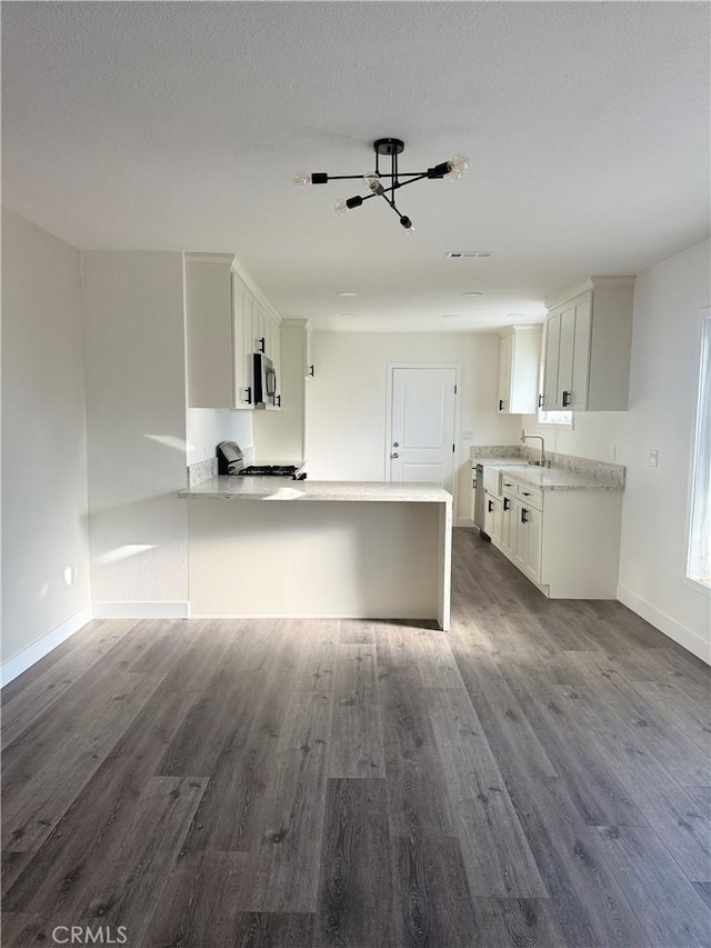 880 S State St, Hemet, CA 92543 - kitchen featuring stainless steel microwave, a peninsula, dark wood-style floors, and light countertops