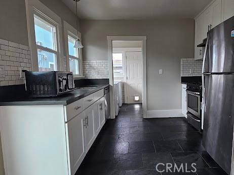 4107 37th St, San Diego, CA 92105 - kitchen with stainless steel appliances, dark countertops, white cabinetry, and backsplash