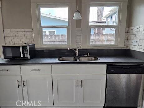 4107 37th St, San Diego, CA 92105 - kitchen featuring stainless steel dishwasher, a sink, dark countertops, white cabinets, and backsplash