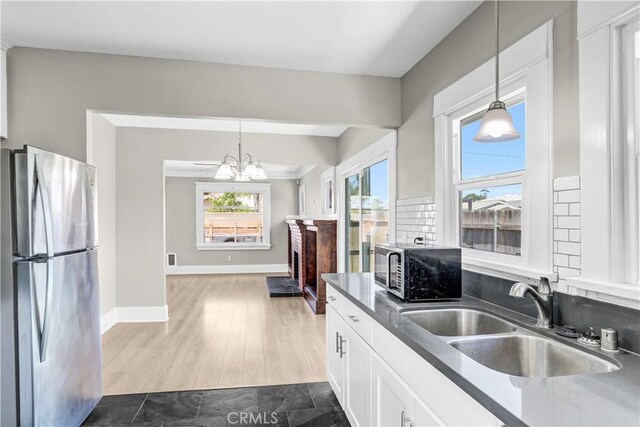 4107 37th St, San Diego, CA 92105 - kitchen with freestanding refrigerator, white cabinets, dark countertops, a chandelier, and decorative light fixtures