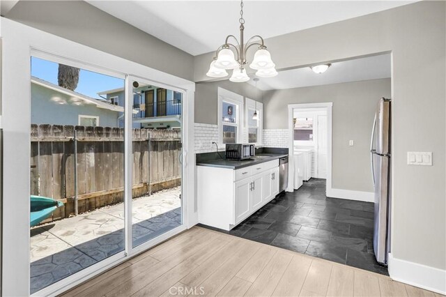 4107 37th St, San Diego, CA 92105 - kitchen with stainless steel appliances, a chandelier, dark countertops, white cabinets, and dark wood finished floors
