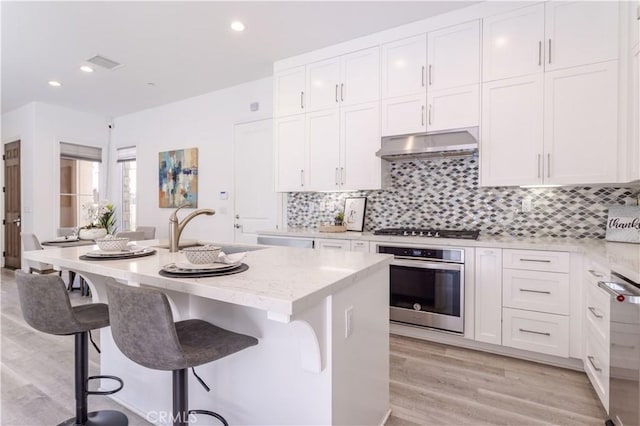 20621 Chestnut Cir, Porter Ranch, CA 91326 - kitchen featuring stainless steel appliances, a sink, under cabinet range hood, white cabinets, and recessed lighting