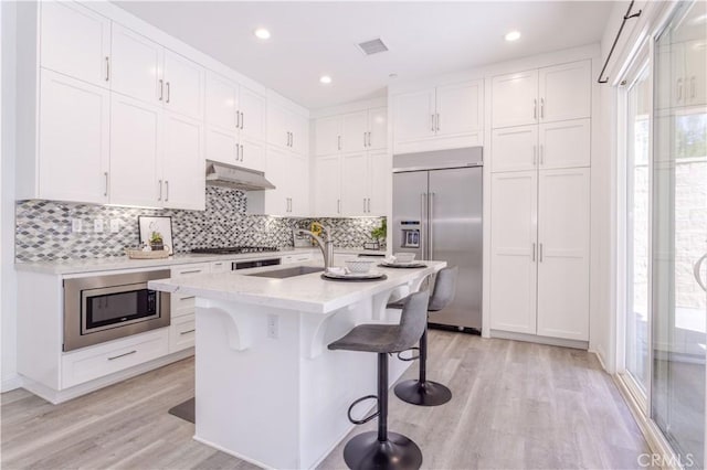 20621 Chestnut Cir, Porter Ranch, CA 91326 - kitchen featuring built in appliances, white cabinets, under cabinet range hood, light wood-style flooring, and recessed lighting