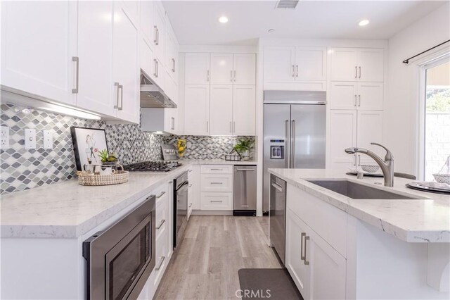 20621 Chestnut Cir, Porter Ranch, CA 91326 - kitchen with a sink, under cabinet range hood, built in appliances, white cabinetry, and light wood-style flooring