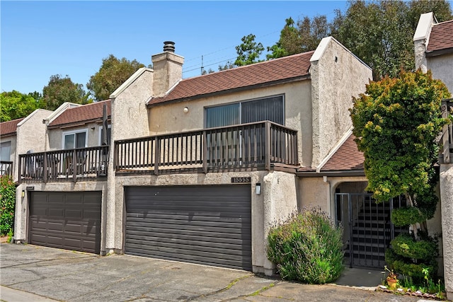 view of front of house featuring a balcony, a garage, a chimney, stucco siding, and concrete driveway