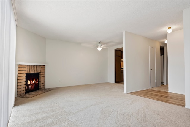 unfurnished living room with light colored carpet, a ceiling fan, and a fireplace