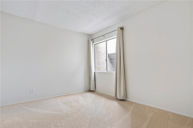 carpeted spare room featuring a textured ceiling and baseboards