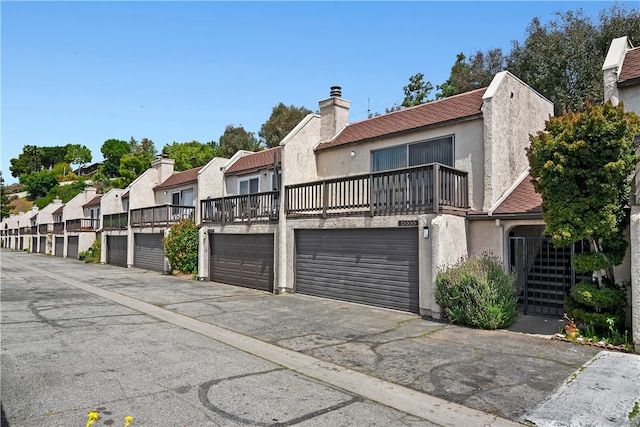 view of property with a balcony, stucco siding, a residential view, and a chimney