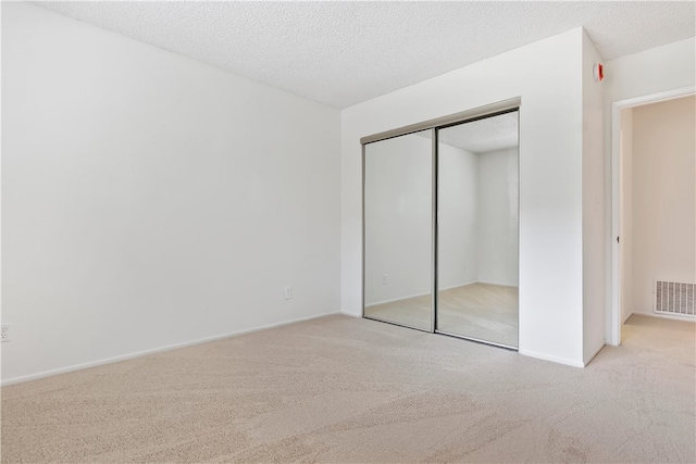 unfurnished bedroom featuring carpet, a closet, baseboards, and a textured ceiling
