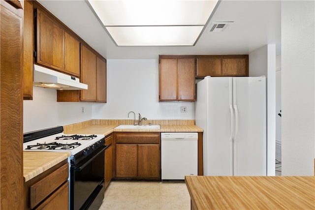 kitchen featuring white appliances, under cabinet range hood, a sink, light countertops, and light floors
