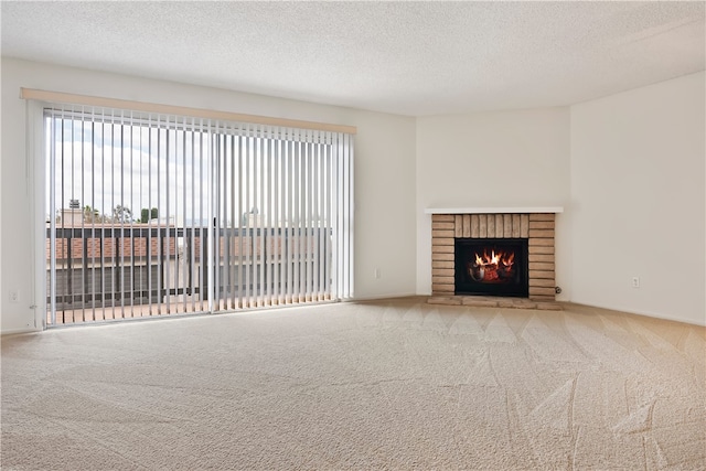 unfurnished living room featuring carpet floors, a textured ceiling, and a brick fireplace