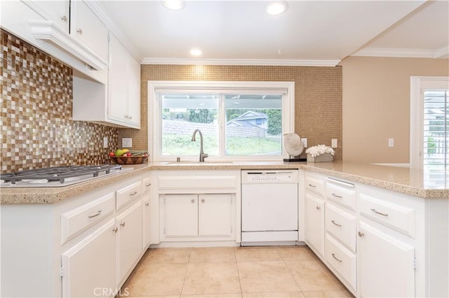 kitchen featuring white appliances, a sink, ornamental molding, light tile patterned floors, and a peninsula