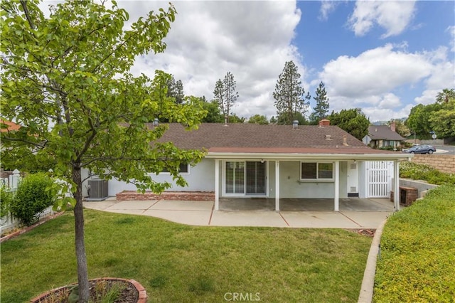 back of property featuring a patio area, a lawn, central AC unit, and stucco siding