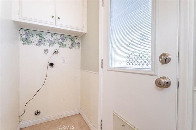 laundry room featuring cabinet space, baseboards, and light tile patterned flooring