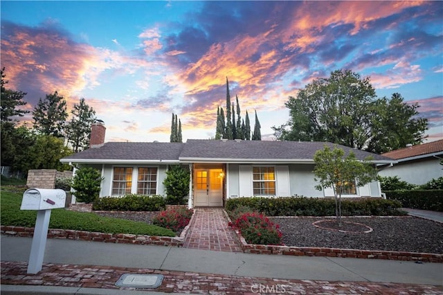 ranch-style home featuring a chimney and stucco siding