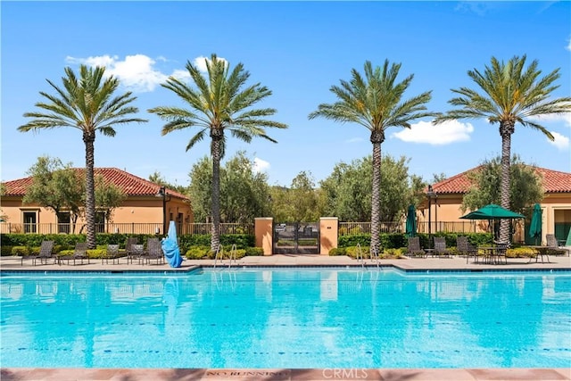 community pool with fence and a patio