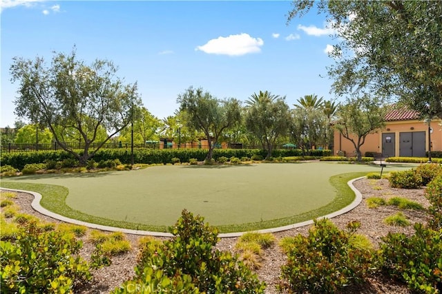 view of home's community featuring an area to practice putting and fence