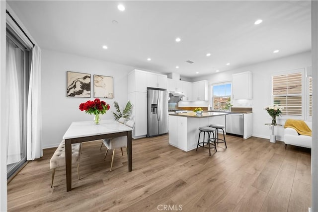 kitchen featuring stainless steel appliances, a kitchen island, white cabinetry, under cabinet range hood, and recessed lighting