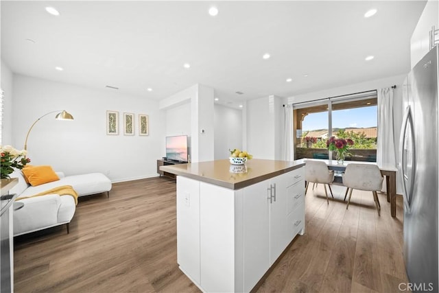 kitchen featuring freestanding refrigerator, recessed lighting, wood finished floors, a kitchen island, and open floor plan