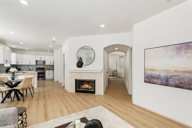 3116 Windhaven Way, Corona, CA 92882 - living room featuring arched walkways, light wood-type flooring, recessed lighting, a tile fireplace, and baseboards