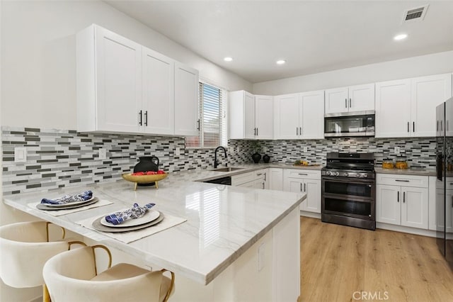 3116 Windhaven Way, Corona, CA 92882 - kitchen featuring stainless steel microwave, double oven range, a peninsula, white cabinets, and decorative backsplash