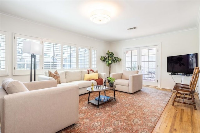 living room with crown molding, wood finished floors, baseboards, and french doors